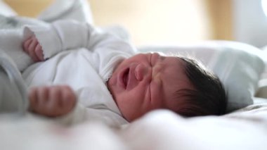 Yeni doğan bebek uyurken rahatsız hisseder, yüzünün kapanışı somurtkanlık gösterir, eski hayatın doğal ifadelerini yakalar, uyuyan bir bebeğin savunmasızlığını ve masumiyetini vurgular.