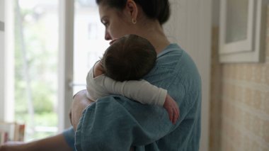 Anne, kucağında bebek uyurken yemek pişiriyor, çocuğunu beslerken ev işlerini yapıyor, ebeveynlik ve günlük sorumlulukların dengesini temsil ediyor.
