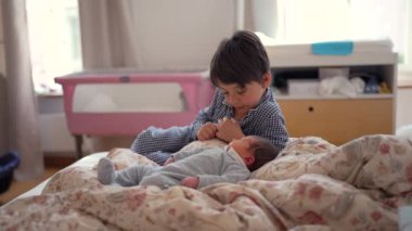 Ağabeyim, yeni doğan kardeşinin yanında, yatakta oturuyor, onları düşünceli bir ifadeyle gözlemliyor, kardeş ilişkisinin ilk aşamalarında sakin ve içsel bir anı yakalıyor.