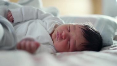Yeni doğmuş bebek, sıcak ve rahat bir ortamda huzurlu bir yatakta, yüzü rahat ve sakin bir şekilde uyur.