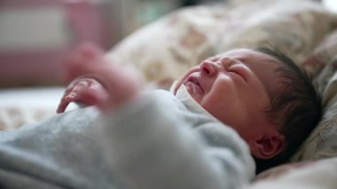 Yeni doğmuş bebek yatakta uzanıyor, esniyor ve esniyor, sakin ve rahat bir ev ortamında, çocukluk döneminin huzurlu ve hassas bir anını yakalıyor.