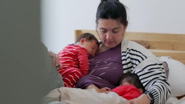 Anne, yeni doğan ve büyük oğlunu kucağında dinlenirken seyrediyor. Huzurlu, samimi bir aile ortamında derin bir annelik bağı, sıcaklık ve sevgi anı yaşıyor.