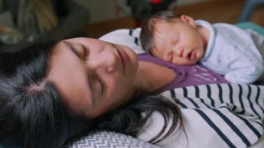 Anne ve yeni doğan bebek bir kanepede yatıyorlar, anne gözle görülür şekilde yorgun, erken yaşta anne olmanın barışçıl ama zorlu anlarını vurguluyor ve aralarında paylaşılan derin bağı vurguluyor.