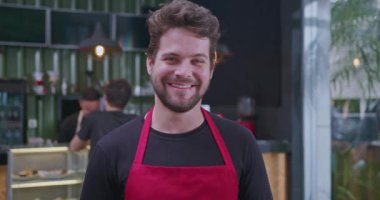 Son moda bir kafede kırmızı önlük giyen arkadaş canlısı barista, sıcaklığı ve mükemmel müşteri hizmetleri veriyor. Konukseverliği, kahve kültürünü ve iş ortamlarını hoş karşılamak için ideal.