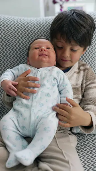 stock image Older brother holding newborn baby, expressing love and care, capturing the beautiful bond and family connection in a cozy home setting