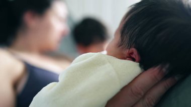 Close-up of a mother and child gazing lovingly at their newborn, with the baby comfortably cradled. blurred background emphasizes the intimate and tender moment shared by the family clipart