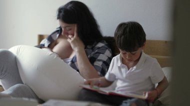 Annesi yeni doğmuş bebeği emzirirken büyük oğlu yanında bir kitap okuyor. Anne, ekose gömlekli, bebeğini büyütüyor, aile hayatının sakin bir anını yakalıyor ve yatakta kardeş ilişkileri kuruyor.