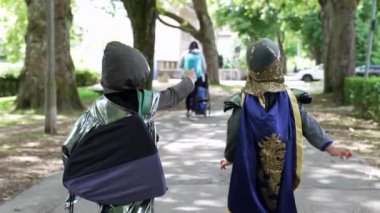 Şövalye gibi giyinmiş iki çocuk bir sonraki maceraları için parkta yürüyorlar. Çocukluğun heyecanı ve hayal gücü, ağaçların ve doğanın bir zeminine kurulur.