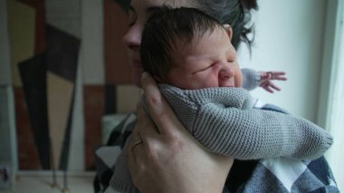 Yeni doğmuş bebeğini kucaklayan bir annenin yakın çekimi, bu samimi anda paylaşılan sevgi ve şefkati gösteriyor.