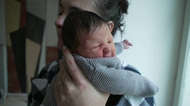 Yeni doğmuş bebeğini kucaklayan bir annenin yakın çekimi, bu samimi anda paylaşılan sevgi ve şefkati gösteriyor.