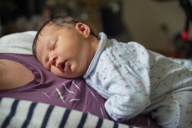 Yeni doğan bebek annesinin göğsünde mışıl mışıl uyuyor. Sevgi dolu bir ortamda ilişkilerinin sükunetini ve bağını gösteriyor.