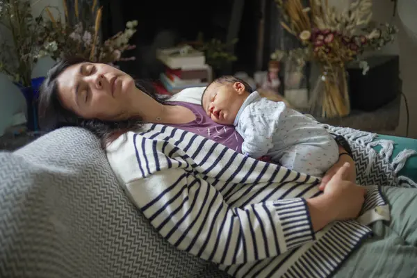 Bebek anne göğsünde huzur içinde uyuyor, sıcak ve rahat bir ortamda güvenlik ve aşkın özünü yakalıyor. İkisi de rahat ve rahat.
