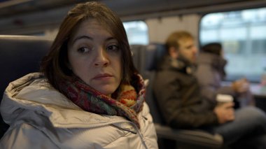 Düşünceli bir ifadeyle trende seyahat eden kadın, her gün seyahat ve toplu taşıma araçlarını yakalıyor, kışlık ceketli ve atkılı kadın yolcu.