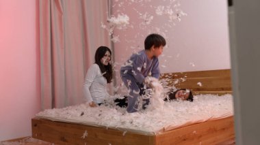 Çocuklar, tüylerle dolu rahat bir yatak odasında, sıcak ve eğlenceli bir ortamda, çocukluk sevincini ve heyecanını ön plana çıkaran, eğlenceli bir yastık kavgası yapıyorlar.