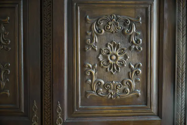 stock image Close-up of detailed floral carvings on an antique wooden wardrobe, highlighting intricate craftsmanship and vintage design in home furniture, suitable for classic interior decor