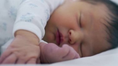 Yeni doğan bebek el ve ayakla uyuyor. Bebeklik döneminin hassas ve nazik doğasını vurguluyor.