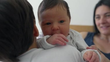 Kardeşlerin omuzlarında dinlenen yeni doğan bebeğe yakın çekim, sıcak kardeş bağı, rahatlatıcı an, bakım, ev ortamları, erken çocukluk, koruyucu bağ, doğal ışık