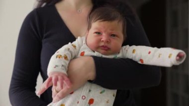 Bir annenin yeni doğmuş bebeğini kucağına alıp anne ve çocuk arasındaki samimi ve hassas bağı vurguladığı yakın plan.