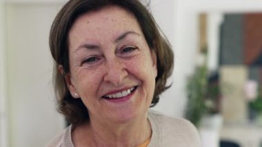 Yaşlı kadın nazikçe gülümsüyor. Nazik ifadesi ve doğal kırışıklıkları bilgeliği, sıcaklığı ve ihtiyarlığın güzelliğini vurguluyor.