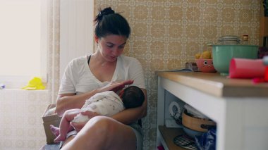 Anne yeni doğmuş bebeğini rahat bir mutfak ortamında nazikçe kucaklıyor ve besliyor, erken yaşta annelik, ebeveynlik bağı ve bebek bakımını sıcak, rahat bir ortamda gösteriyor.