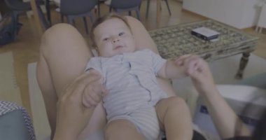 Anne kucağında bebekle oynuyor. Sıcak bir ev ortamında birlikte eğleniyor ve gülüyor. Aile bağlarının sıcaklığı.