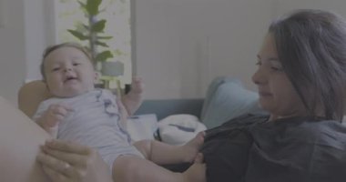 Anne bebekle kanepede uzanıyor, huzurlu bir evde dinleniyor, sıcak ve rahat bir oturma odasında sessiz bir bağ kurma zamanını paylaşıyor.