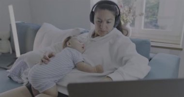 Anne, bebeğin göğsünde uyuması, kulaklık takması, dizüstü bilgisayarda çalışması, rahat ev ortamında çalışması, işi dengelemesi ve ebeveynliği