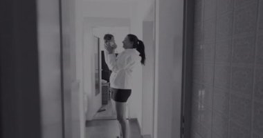 Anne bebeğini loş bir koridorda neşeli ve şefkatli bir anı paylaşarak kaldırıyor. Siyah ve beyaz ayarı duygusal bağlarını ve bağlantılarının basitliğini vurgular.