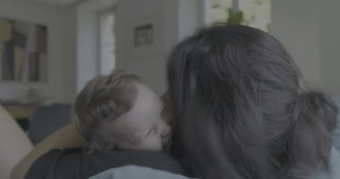 Anne kucağında bebekle kanepede uzanıyor. Huzurlu ve huzurlu bir yuva kurma anını paylaşıyor.