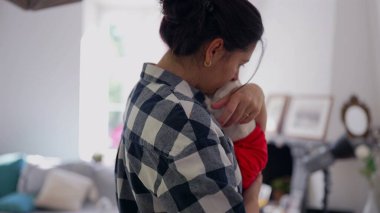 Anne, yeni doğmuş bebeği nazikçe kucağına alıp huzurlu bir yuvada sevgi ve bağ kuruyor.