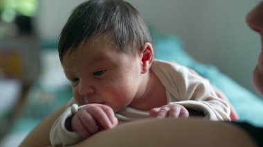 Anne yeni doğmuş bebeği kucağında tutuyor, ikisi de sakin ve huzurlu görünüyor. Yumuşak bir kucaklama ve sıcak bir yuva kurmak anne ve çocuk arasındaki sevgi bağını vurgular, barışçıl bir atmosfer yaratır.