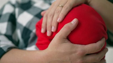 Bir annenin elinin yakın çekimi yeni doğan bebeğini nazikçe alt açıdan sarkıtıyor. Bağlarında şefkat ve özen