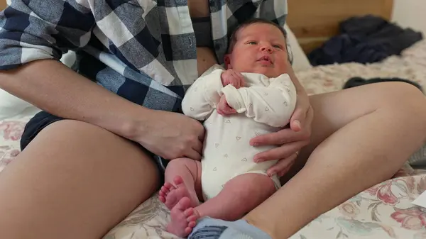 stock image Newborn baby lying in a parent's lap, dressed in a white onesie, showing a close bond and comfort in a cozy, nurturing environment