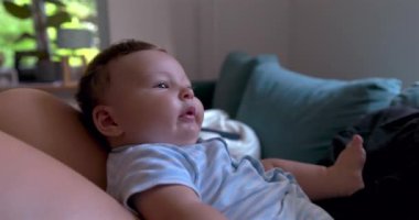 Anne oynarken bebeğini yüzüne yakın tutuyor, sıcak, aile dostu bir oturma odasında sevgi ve bağ anları, doğal ışıklandırma.