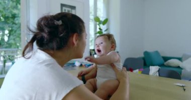 Anne bebeğine sıkıca sarılıyor. İkisi de hassas bir anda. Sıcak bir evin penceresinden süzülen doğal ışıkla.
