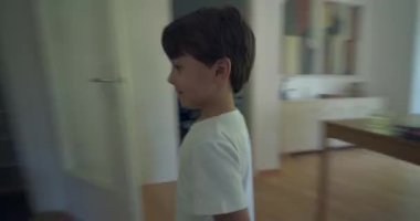 Çocuk bir evin koridorunda koşuyor, bir çocuğun enerji ve heyecanla mutfağa doğru koşuşunu bulanıklaştırıyor. Çocukluk hareketlerini ve hareketlerini gösteren ev içi sahneler