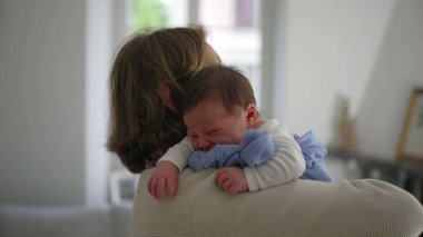 Anneanne kucağında ağlayan yeni doğan bebek, geriye bakış, bebeği rahatlatan ev, şefkatli an, anne bakımı, aile bağı