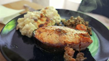 Izgara somon bifteği kremalı patates püresi ve yanında havuçlu sotelenmiş mercimek ile servis edilir. Dengeli ve besleyici bir yemek sunumu sunar. 