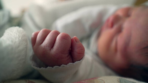 Close-up of a newborn baby's hand as they sleep peacefully on a bed. tiny hand is the focus, highlighting the delicate and tender aspects of early life and new beginnings