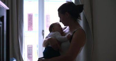 Anne, uyuyan bebeğini kafasından öper, pencerenin yanında durup sevgi ve şefkat göstererek, gün ışığıyla sahneyi aydınlatır.