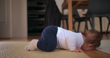 Bebek yüzüstü yatar, kafası hayal kırıklığına uğrar, huzurlu bir ev ortamında yumuşak bir paspas üzerinde emekleme girişiminde bulunurken duygularını ifade eder.