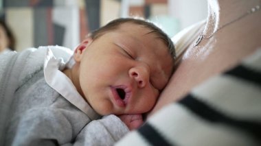 Yeni doğan bebek, anne-çocuk ilişkisinin yakınlığını ve sükunetini vurgulayarak, doğal ışıkla anne göğsüne rahatça uzanır.