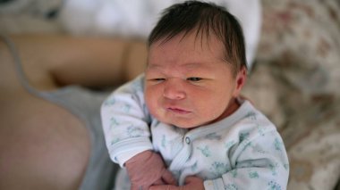 Close-up of a newborn baby transitioning from crying to calm while being held by mother. Intimate scene of early parenthood, focusing on the emotional shifts and challenges of newborn care clipart