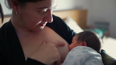 Anne yeni doğan bebekleri emziriyor, anne ve çocuk arasındaki doğal ve sevgi dolu bağın barışçıl bir ortamda yansıtıldığı samimi bir ortam yaratıyor.