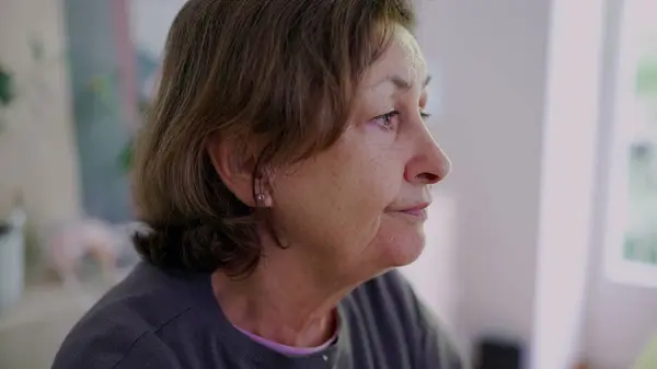 stock image Close-up of an elderly woman in deep thought, resting her chin on her hand. a reflective and pensive moment, highlighting the quiet contemplation of everyday life