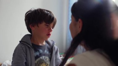 Üzüntüsünü ifade eden çocuk, hafifçe sakinleşti ve destekleyici bir etkileşimle annesine doğru uzandı. Bir anne ve çocuk arasındaki hassas bir an.