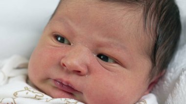 Yeni doğan bebek yavaşça merakla bakıyor, huzurlu bir evde dinleniyor, sakin ve sıcak bir anı yakalıyor.