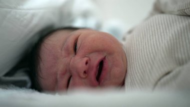 Yatakta ağlayan yeni doğmuş bir bebeğin yakınlaşması rahatsızlık ve üzüntüyü ifade eder. Samimi an, bebekliğin kırılganlığını ve ham duygularını vurgular.