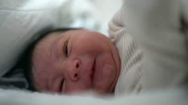 Yatakta ağlayan yeni doğmuş bir bebeğin yakınlaşması rahatsızlık ve üzüntüyü ifade eder. Samimi an, bebekliğin kırılganlığını ve ham duygularını vurgular.