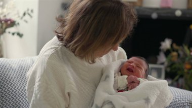 Büyükannem yeni doğan bebeğe hafifçe gülümsüyor, sıkıca sarılıyor ve huzurlu bir bağ anının tadını çıkarıyor.